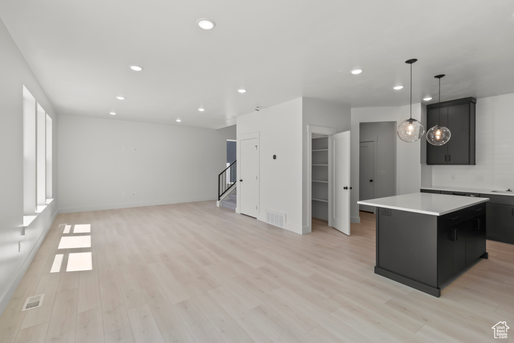 Kitchen with a center island, recessed lighting, light countertops, dark cabinetry, and light wood-style flooring