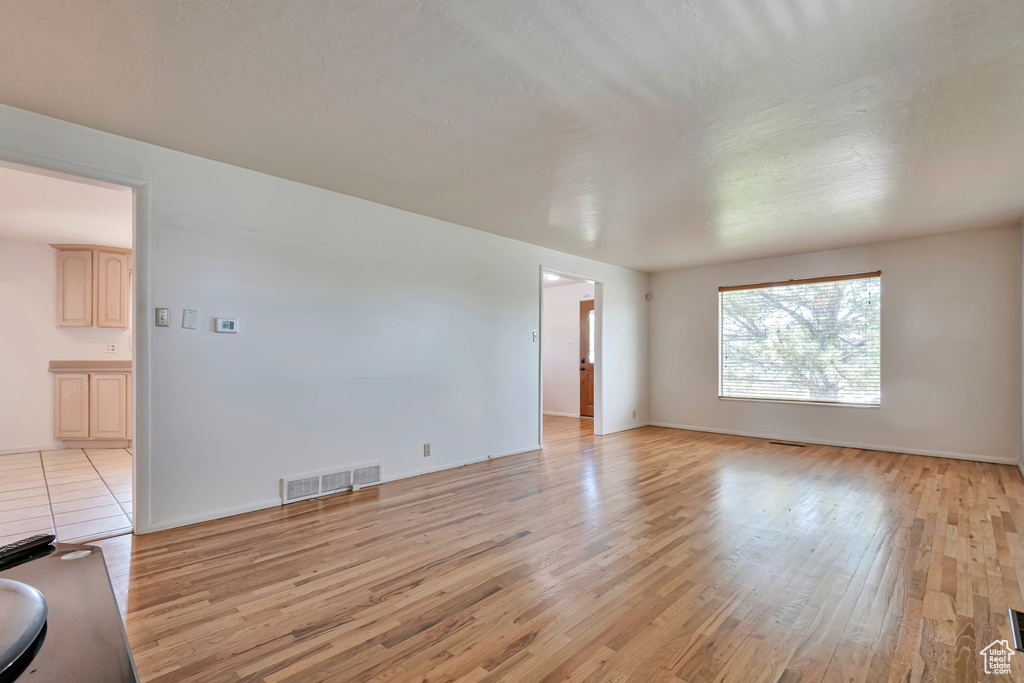 Unfurnished living room featuring light wood-style floors and baseboards