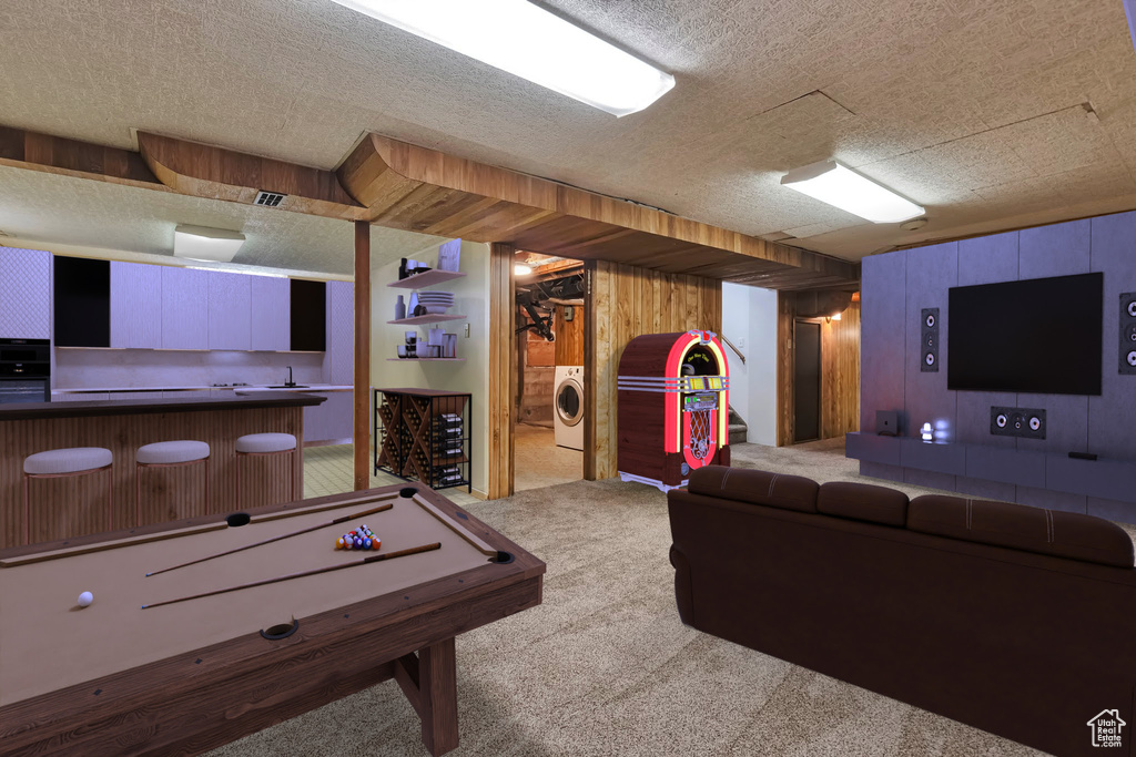 Recreation room with washer / clothes dryer, carpet flooring, a textured ceiling, wood walls, and bar