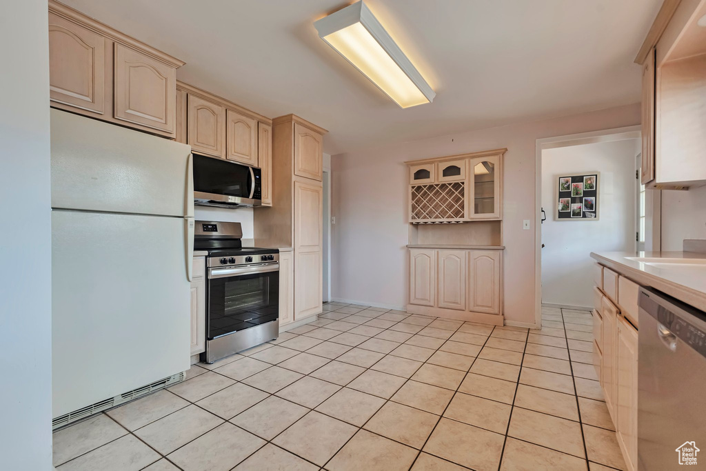 Kitchen featuring stainless steel appliances, light tile patterned floors, light countertops, and light brown cabinets