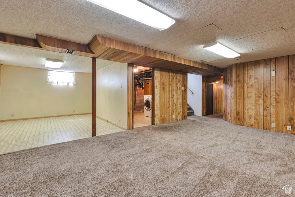 Basement with washer / dryer, carpet flooring, wood walls, stairway, and a textured ceiling