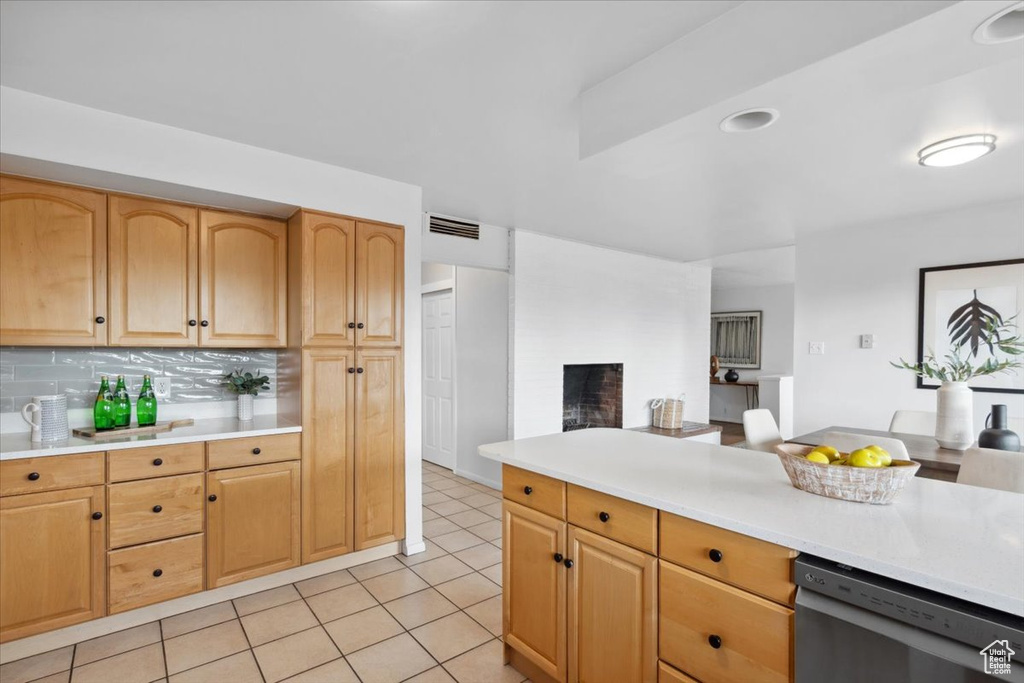 Kitchen with dishwashing machine, light countertops, open floor plan, light tile patterned flooring, and a fireplace