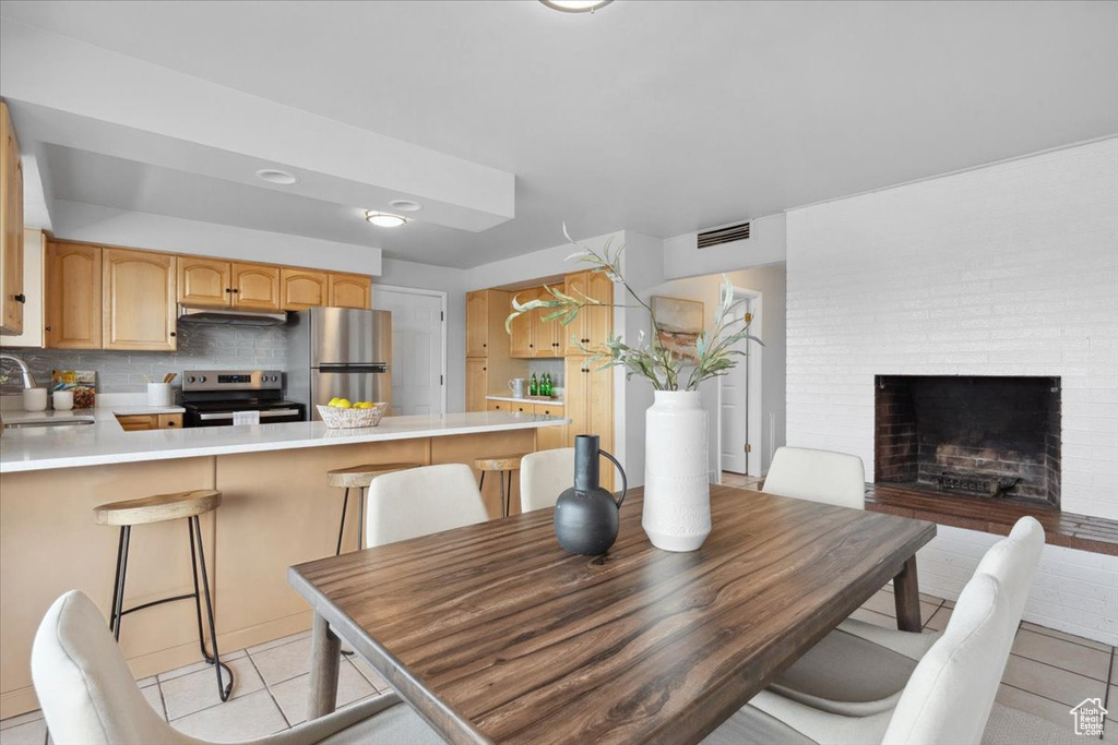 Dining room featuring light tile patterned floors and a brick fireplace