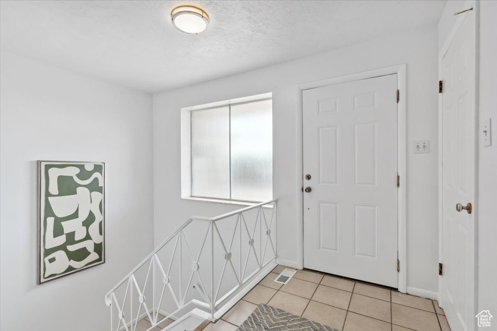 Foyer with light tile patterned floors and baseboards