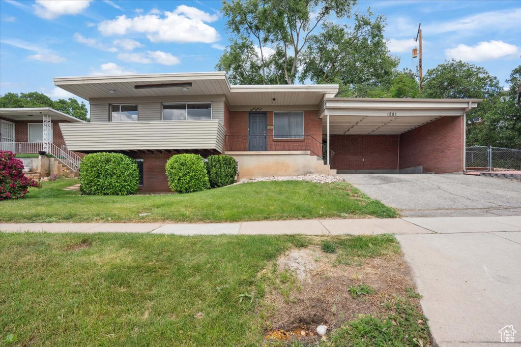 View of front of house featuring brick siding, a carport, and asphalt driveway