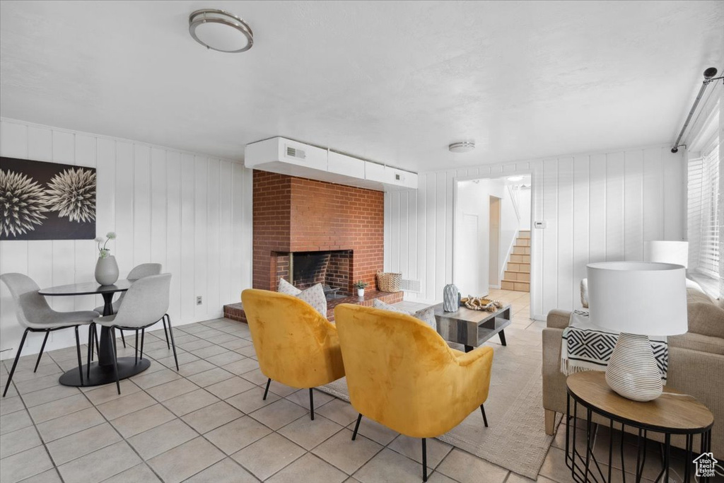 Living room featuring stairway, a brick fireplace, and light tile patterned floors