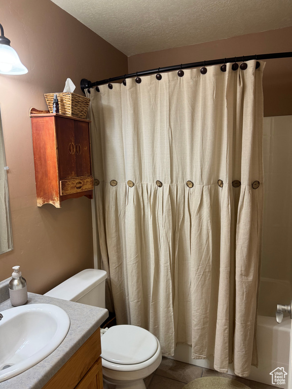 Bathroom featuring vanity, a textured ceiling, shower / tub combo with curtain, and tile patterned flooring