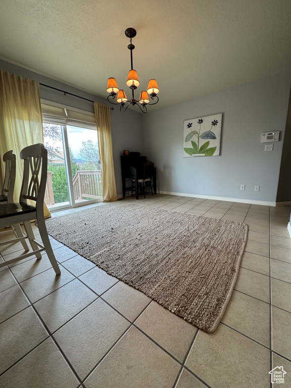 Unfurnished living room with tile patterned flooring, a chandelier, a desk, and a textured ceiling