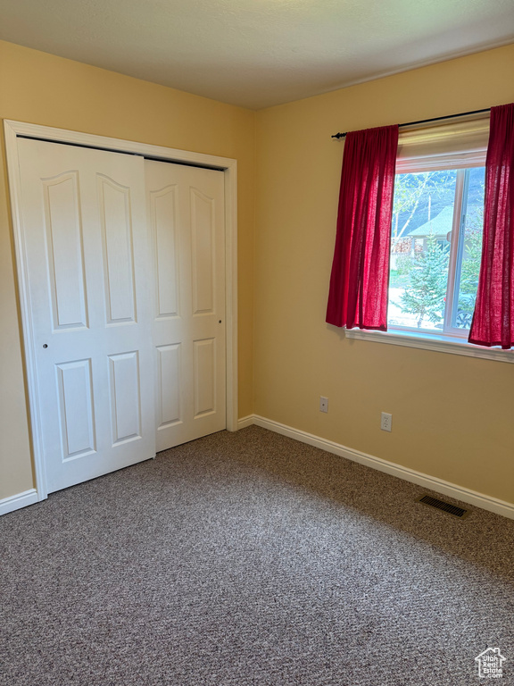 Unfurnished bedroom featuring carpet and a closet