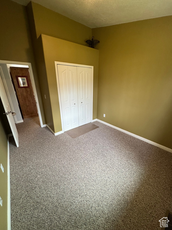 Unfurnished bedroom featuring a closet, carpet, and a textured ceiling