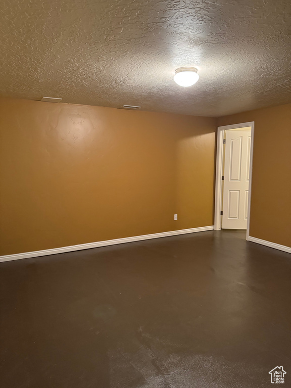 Spare room featuring a textured ceiling and concrete flooring