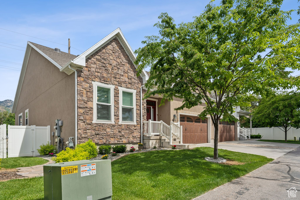 View of front of home featuring stone siding, an attached garage, concrete driveway, stucco siding, and a gate