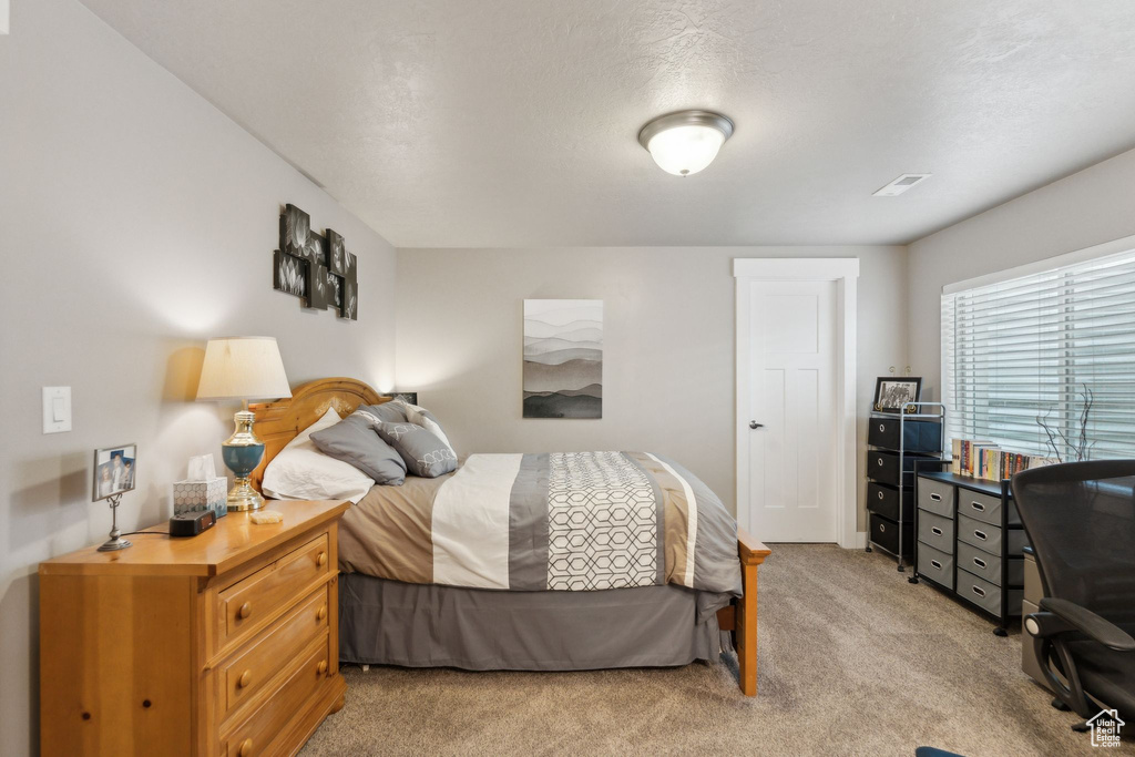 Bedroom with light carpet and an office area
