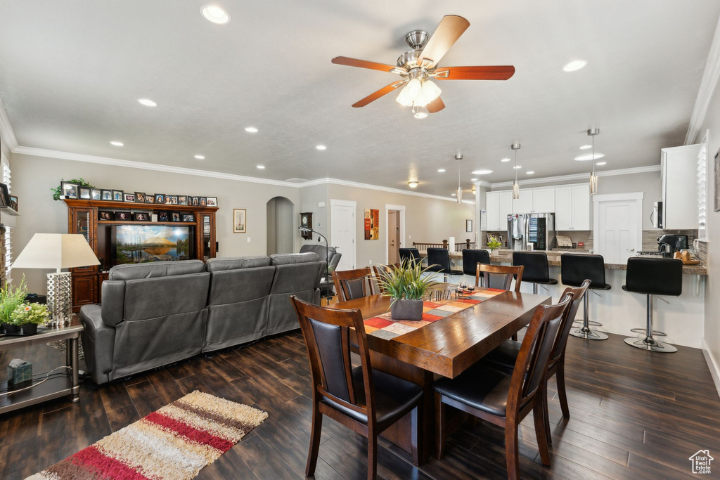 Dining area with recessed lighting, ceiling fan, dark wood-style floors, ornamental molding, and arched walkways