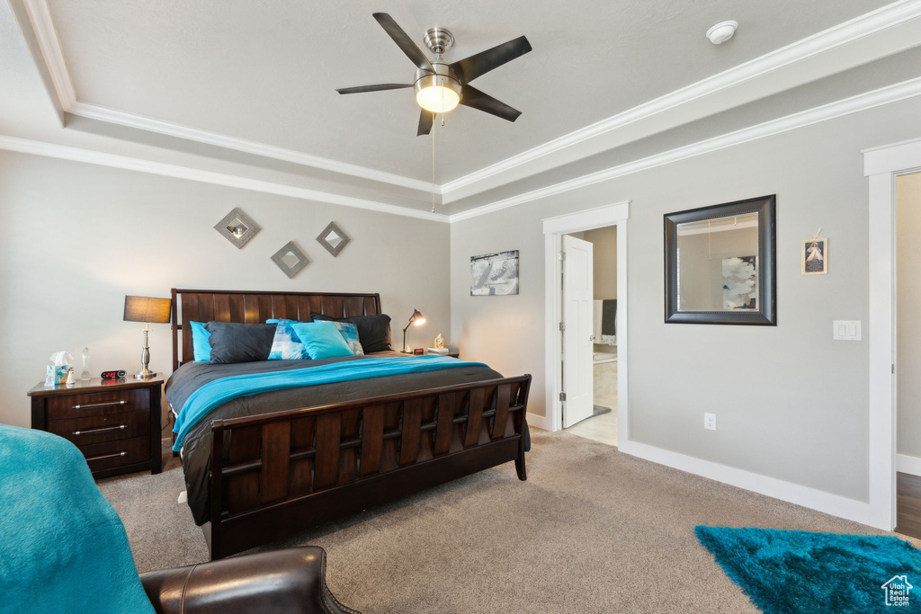 Bedroom featuring a tray ceiling, ornamental molding, carpet floors, baseboards, and connected bathroom