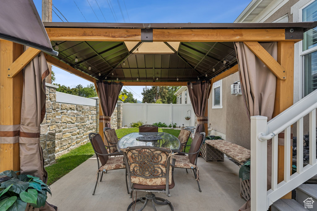 View of patio / terrace with outdoor dining area, a gazebo, and a wall mounted air conditioner