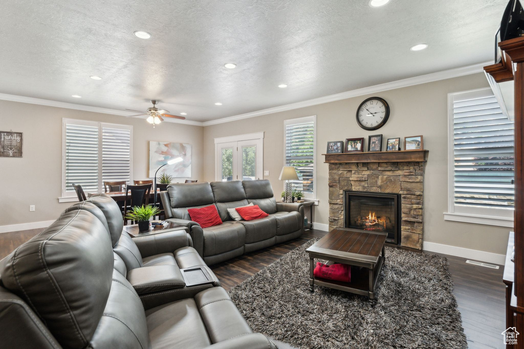 Living area with recessed lighting, dark wood-style floors, a stone fireplace, ceiling fan, and baseboards