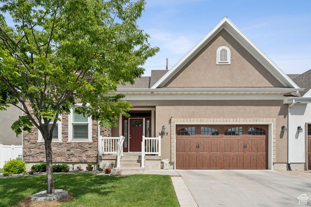 View of front of home featuring stucco siding, driveway, a garage, and a front lawn