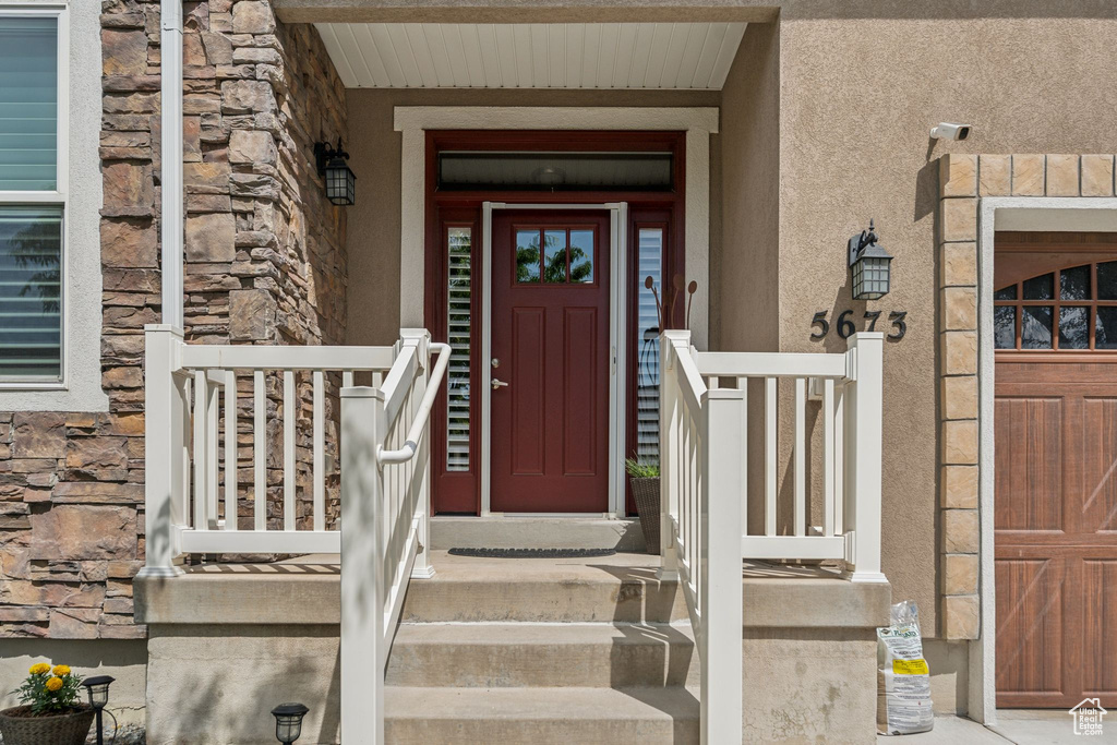 View of exterior entry with stucco siding and stone siding