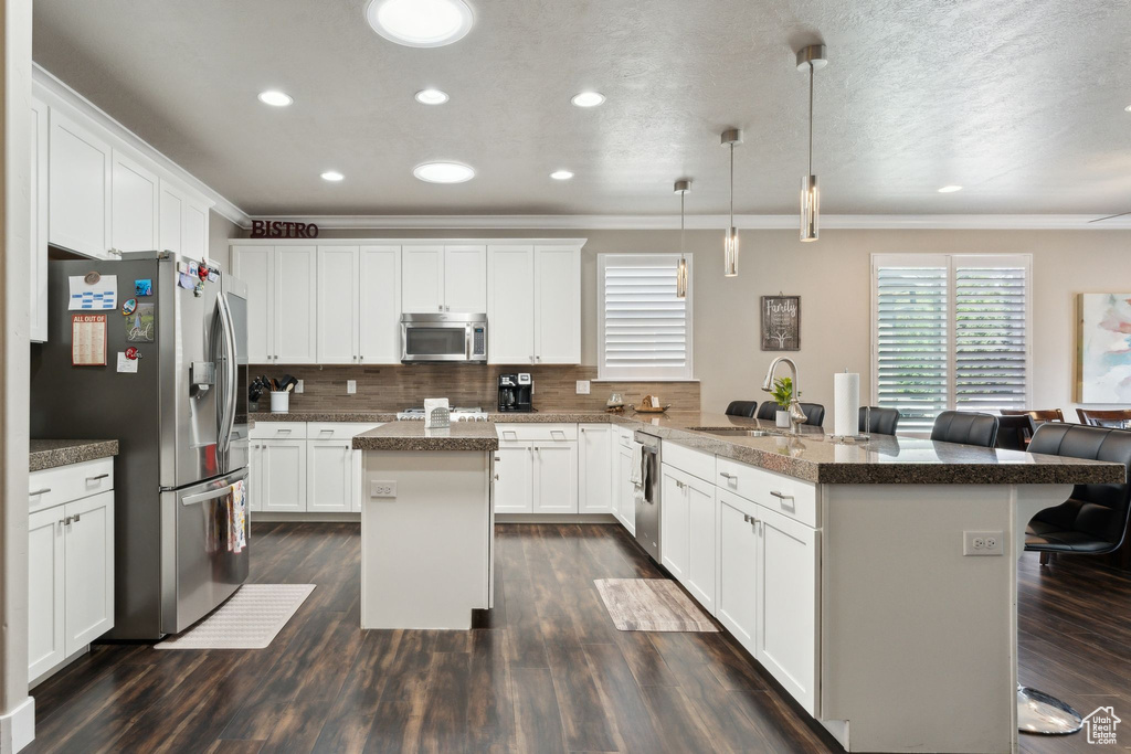 Kitchen with stainless steel appliances, crown molding, a breakfast bar, a peninsula, and decorative backsplash