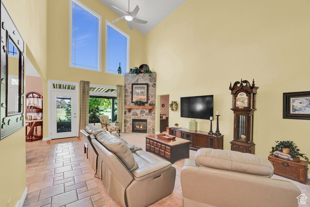 Living room featuring high vaulted ceiling, a ceiling fan, and a stone fireplace