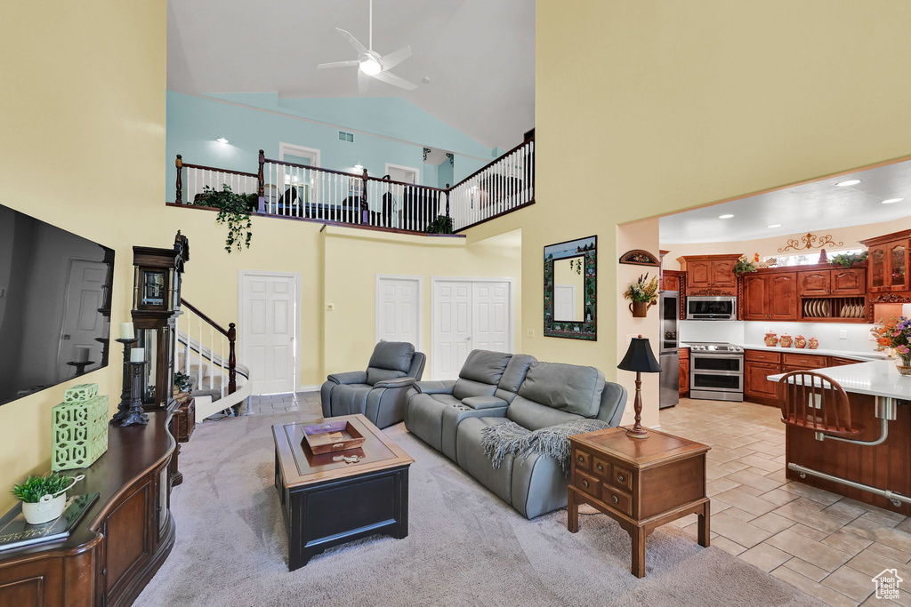 Living area featuring stairs, ceiling fan, and high vaulted ceiling