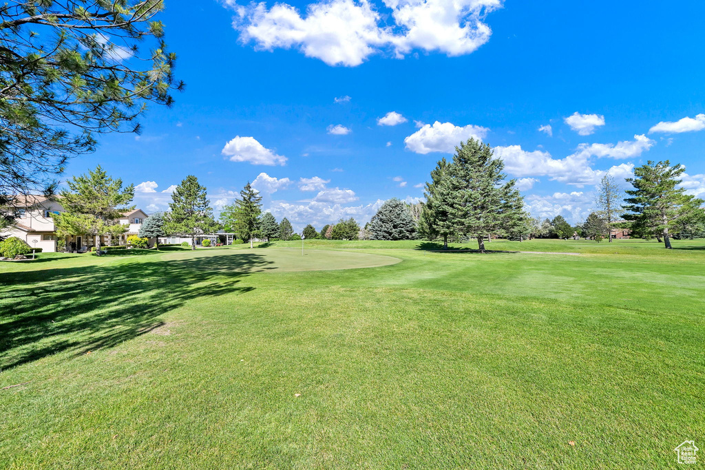 Surrounding community with an area to practice putting, a yard, and view of golf course