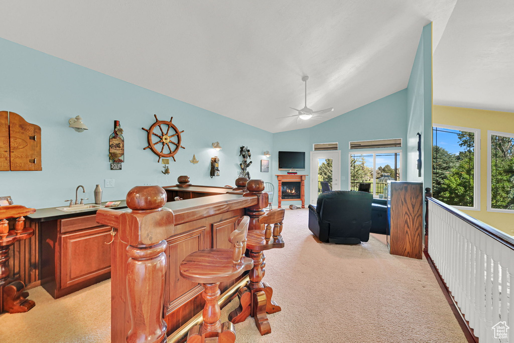 Bar with light colored carpet, a glass covered fireplace, a ceiling fan, and lofted ceiling