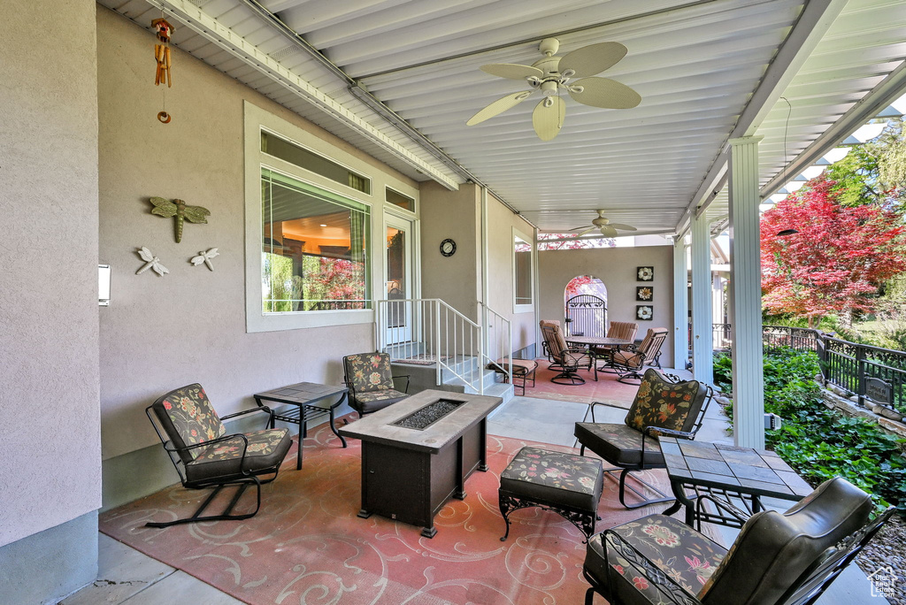 View of patio with ceiling fan, a fire pit, and outdoor dining area