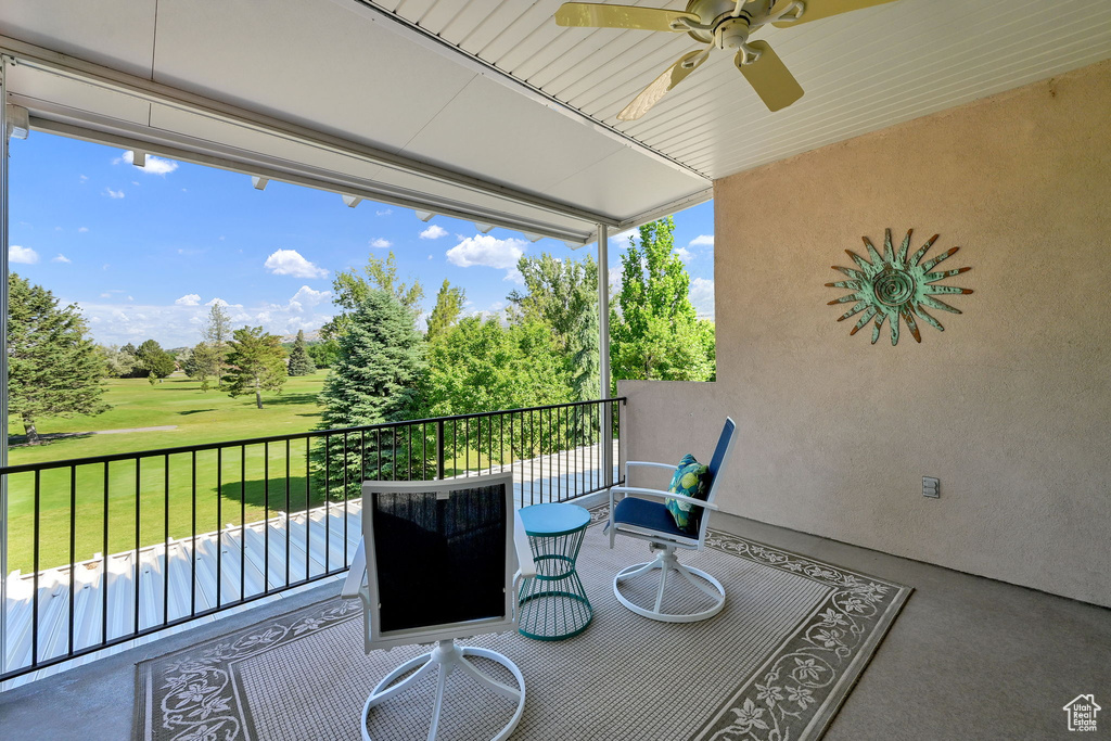 Patio / terrace featuring ceiling fan, golf course view, view of scattered trees, and a yard