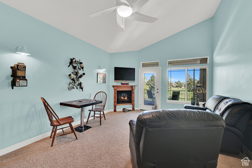 Carpeted living area with a ceiling fan, a glass covered fireplace, and high vaulted ceiling