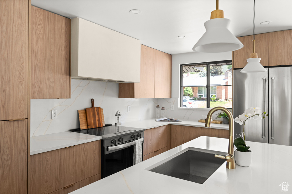 Kitchen with electric stove, high end refrigerator, light countertops, modern cabinets, and tasteful backsplash