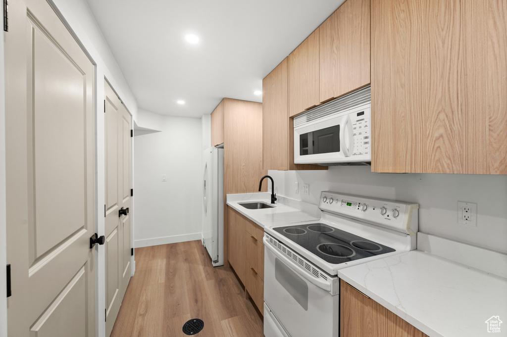 Kitchen featuring white appliances, light wood-type flooring, recessed lighting, light stone counters, and light brown cabinetry