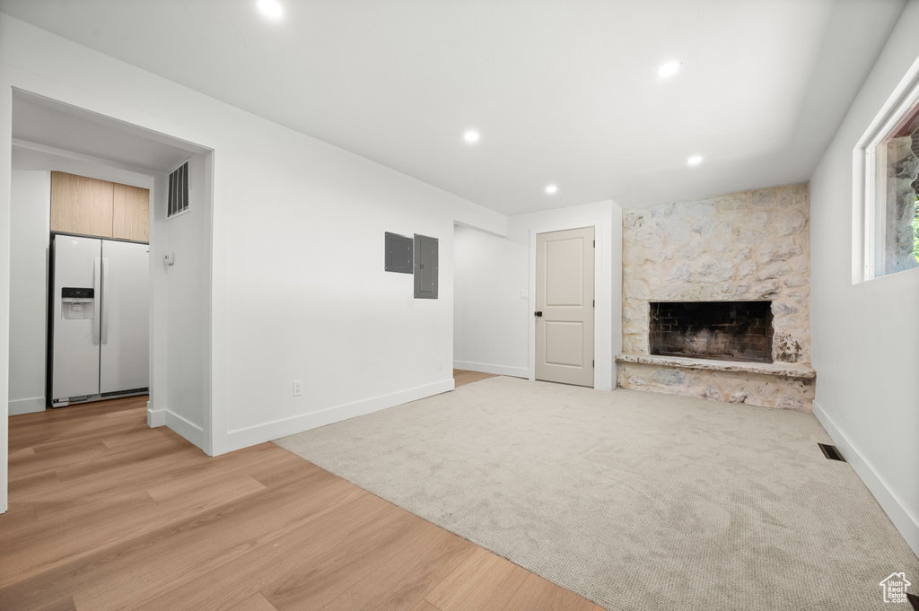 Unfurnished living room with a fireplace, electric panel, recessed lighting, and light wood-type flooring