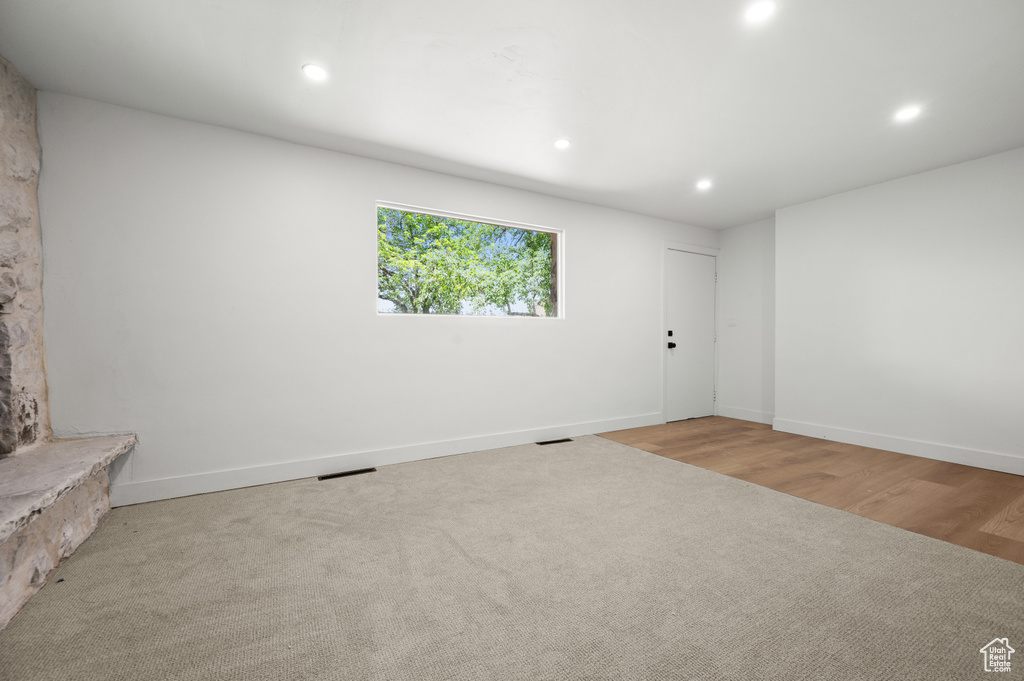 Empty room with recessed lighting, wood finished floors, and carpet