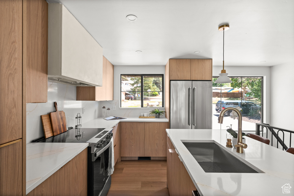 Kitchen featuring high end fridge, electric stove, modern cabinets, dark wood-style floors, and wall chimney exhaust hood
