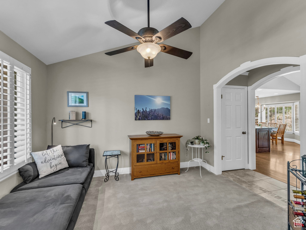 Living area with a ceiling fan, arched walkways, and high vaulted ceiling
