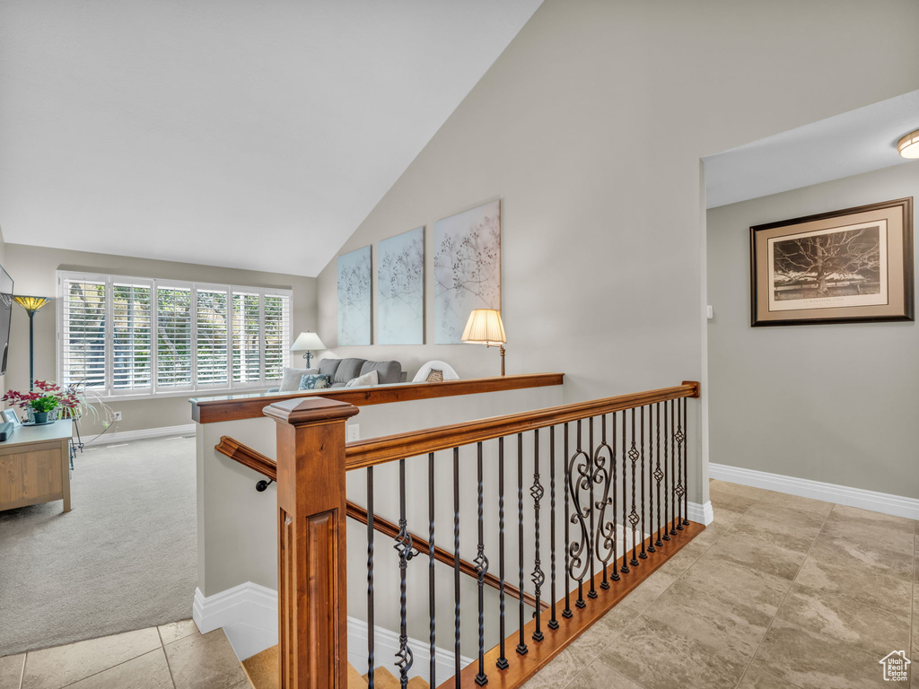 Hall featuring an upstairs landing, high vaulted ceiling, and carpet flooring