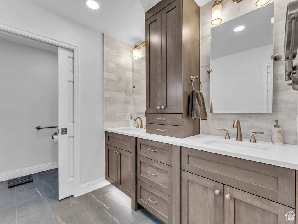 Bathroom with double vanity and marble look tile flooring