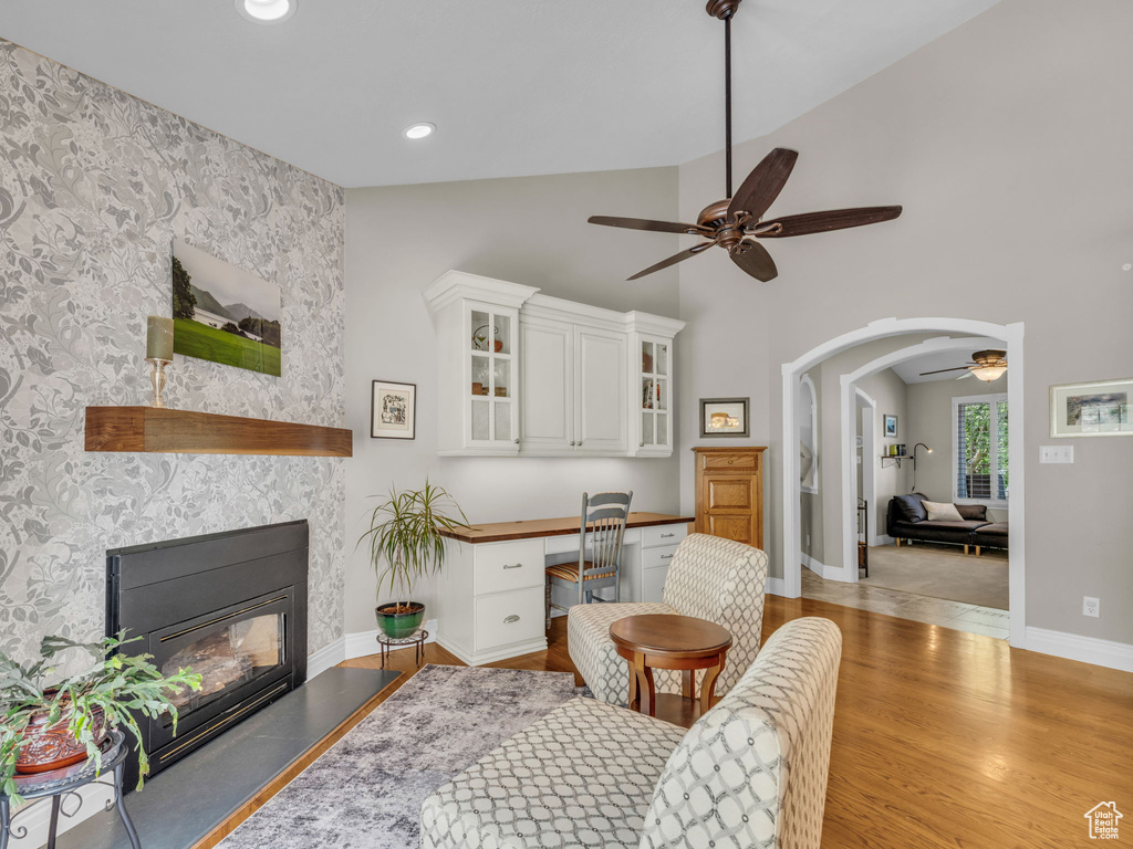 Living room featuring a ceiling fan, light wood finished floors, built in desk, a fireplace, and recessed lighting