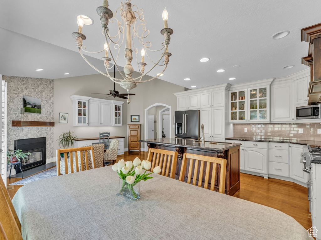 Dining space featuring a fireplace, arched walkways, recessed lighting, a chandelier, and ceiling fan