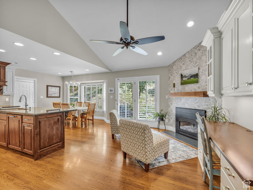 Living area featuring a ceiling fan, light wood-style flooring, recessed lighting, vaulted ceiling, and a large fireplace