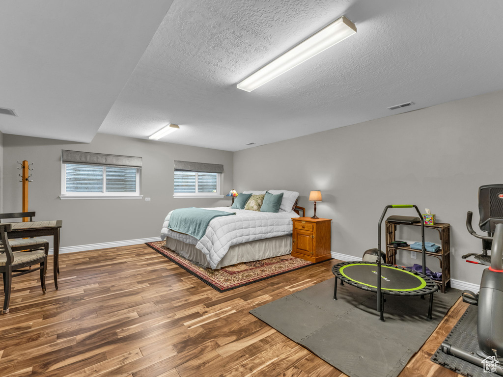 Bedroom with wood finished floors and a textured ceiling