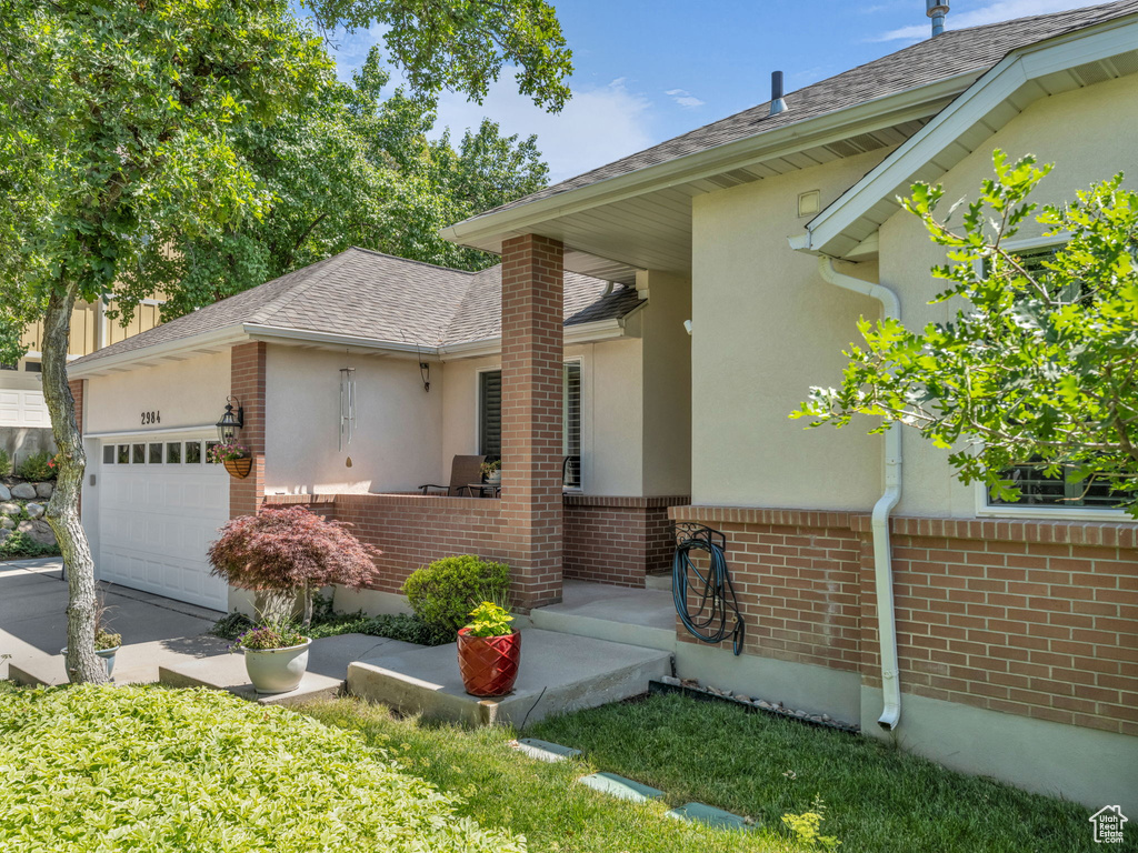 View of front facade featuring stucco siding, an attached garage, brick siding, and a shingled roof