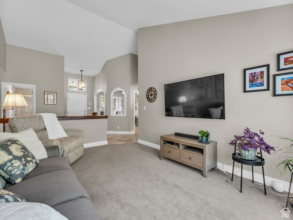 Living room with carpet, a chandelier, and high vaulted ceiling