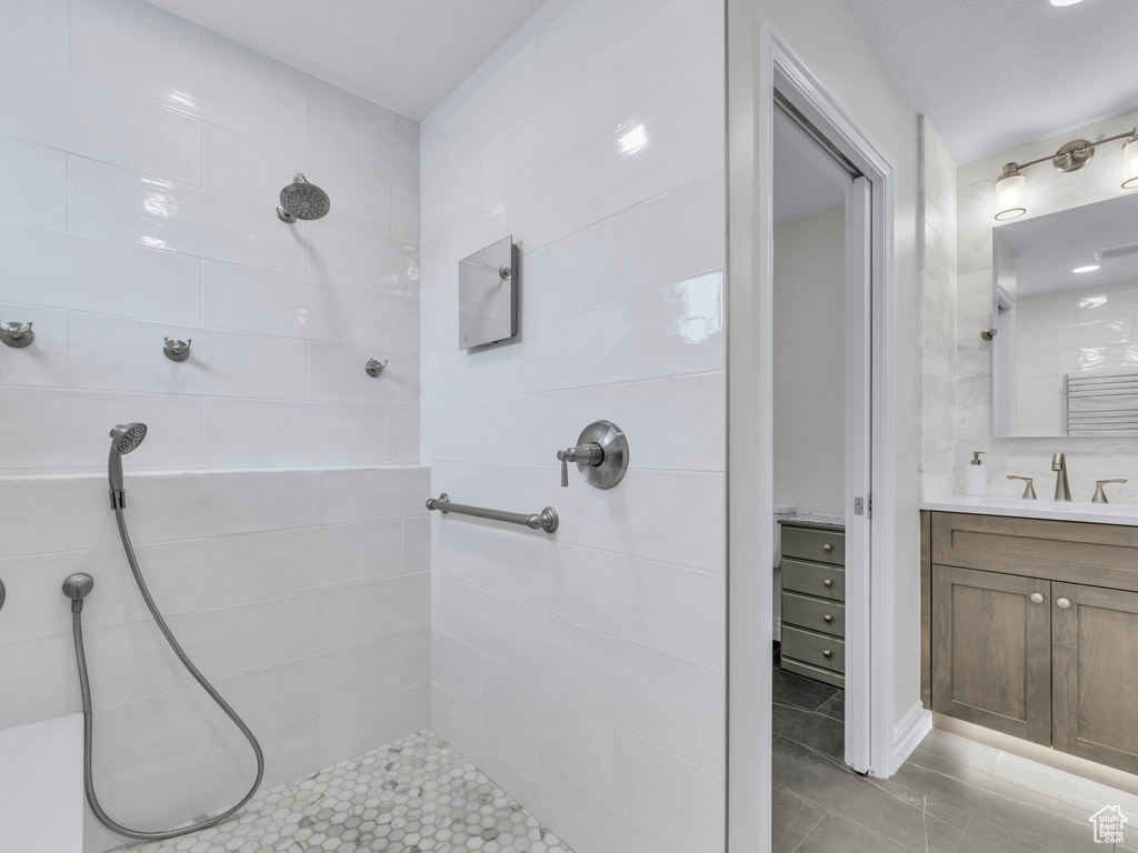 Full bathroom featuring tiled shower, vanity, and tile patterned flooring