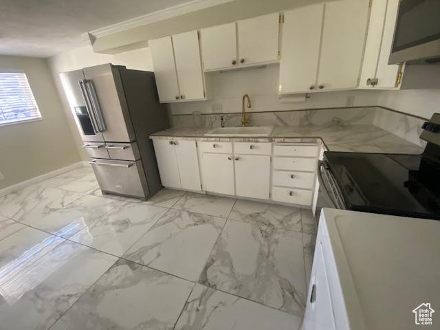Kitchen featuring stainless steel appliances, light countertops, white cabinets, light marble finish floors, and ornamental molding