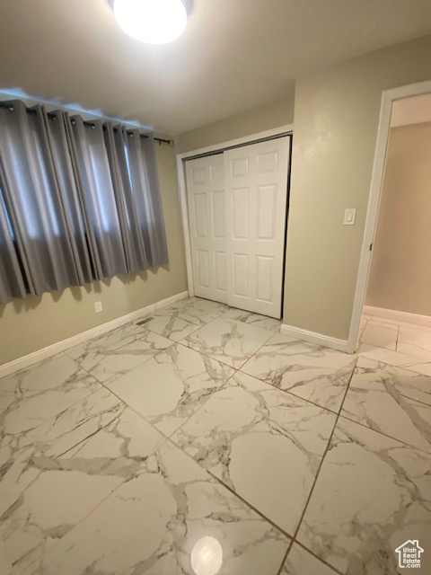 Unfurnished bedroom featuring a closet and light marble finish flooring