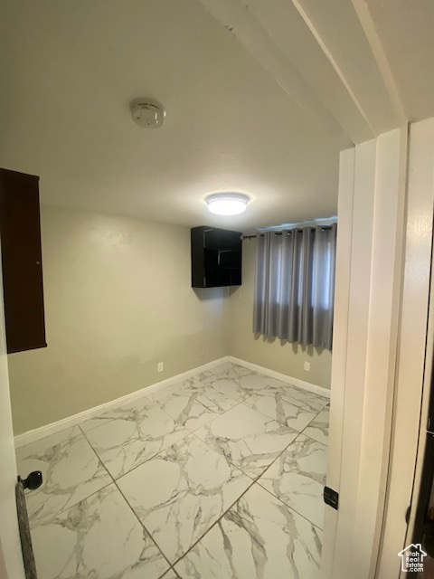 Unfurnished room featuring a smoke detector and marble look tile flooring