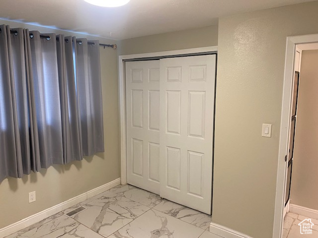 Unfurnished bedroom with light marble finish flooring and a closet